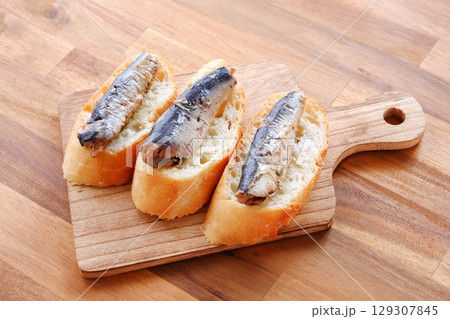 オイルサーディンとバゲット - イワシをオリーブオイルに漬けたオイルサーディンと、焼きたてのバゲット 129307845