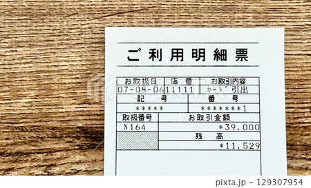 銀行ATMのご利用明細票_茶色板背景俯瞰 銀行ATMのご利用明細票_茶色板背景俯瞰 129307954