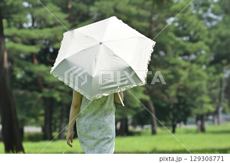 日傘をさして散歩する若い女性 129308771