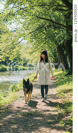 公園で犬の散歩をする若い女性 129308920