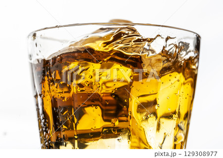 白背景で麦茶の入ったグラスに氷を入れる瞬間 129308977