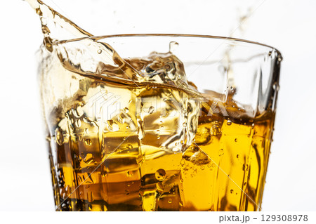 白背景で麦茶の入ったグラスに氷を入れる瞬間 129308978
