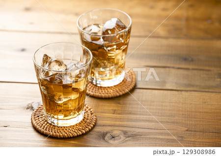 明るい木目テーブルに並べた氷入りの麦茶グラス 129308986