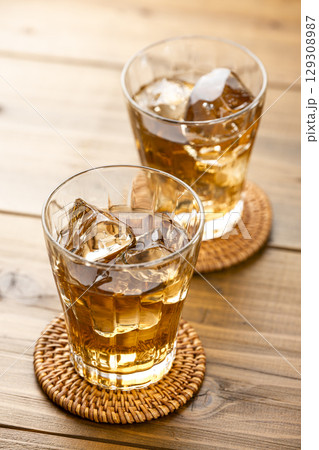 明るい木目テーブルに並べた氷入りの麦茶グラス 129308987