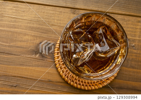 真俯瞰で撮影した氷入りの麦茶グラスと木目テーブル 129308994
