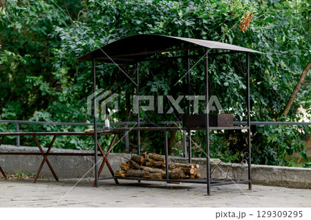 Barbecue area. Metal structure with barbecue and woodpile Barbecue area. Metal structure with barbecue and woodpile 129309295