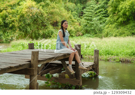 woman resting on edge of wooden jetty woman resting on edge of wooden jetty 129309432