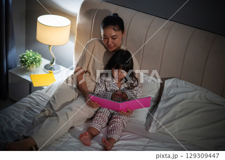 mother read story in the book for toddler girl on bed at night mother read story in the book for toddler girl on bed at night 129309447