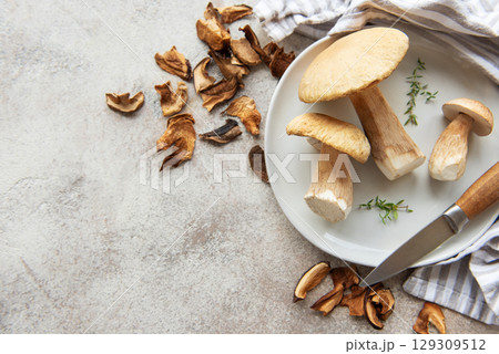 Fresh mushrooms on plate with dried mushrooms and knife 129309512