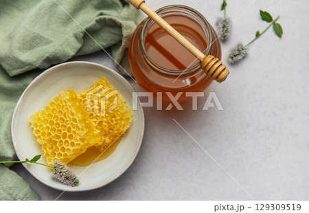 Honeycomb and honey jar with wooden dipper on marble table 129309519