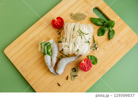 Protein lunch rice noodles shrimp tomato halves on a green background Protein lunch rice noodles shrimp tomato halves on a green background 129309837