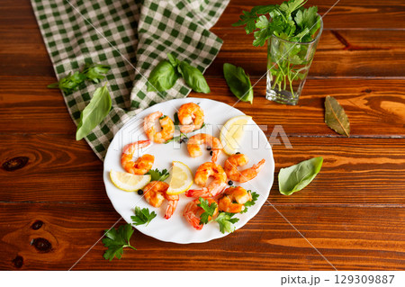 Juicy fried shrimps with lemon slices in a plate on a wooden 129309887