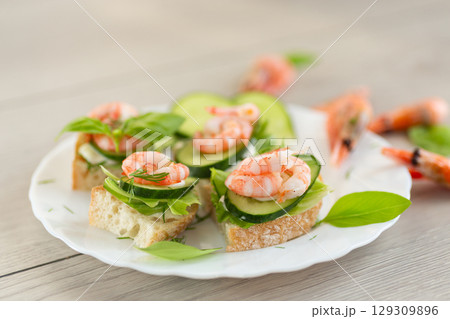 Light festive canapes with seafood, greens and fresh vegetables Light festive canapes with seafood, greens and fresh vegetables 129309896