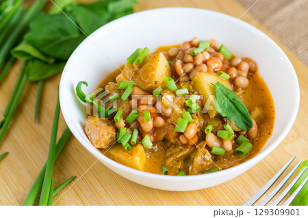 Vegetable stew with meat and potatoes in a white bowl on the table 129309901