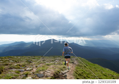 Collage of man in light shirt running away on mountain summit trail with rays breaking through clouds 129310109