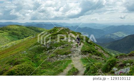Collage of man in black hoodie trail running across mountain ridge under dramatic cloudy sky 129310112