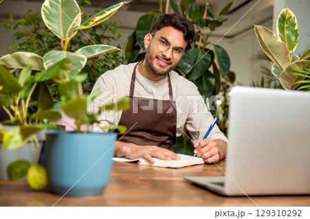 Young man sitting at the laptop in the flower shop 129310292