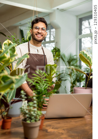 Young man in eyeglasses in the flower shop looking contented and smiling 129310405