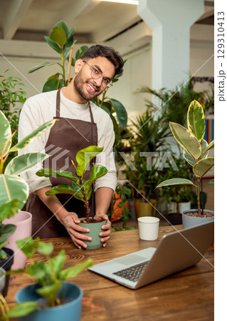 Flower shop assistant presenting plants to the audience in internet 129310413