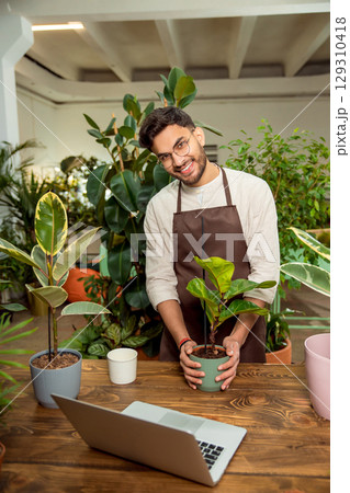 Flower shop assistant presenting plants to the audience in internet 129310418