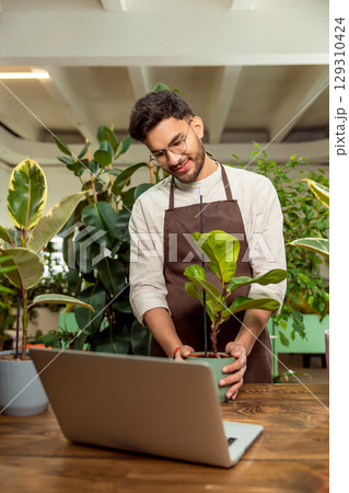 Flower shop assistant presenting plants to the audience in internet 129310424