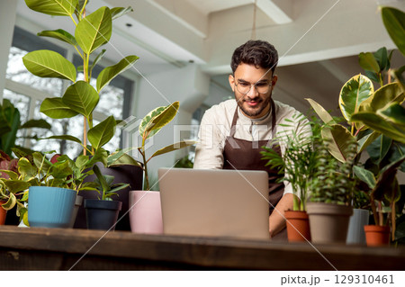 Male shop assistant in the flower shop working on a laptop 129310461