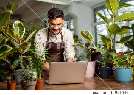 Male shop assistant in the flower shop working on a laptop 129310463