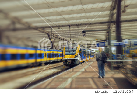 ROTTERDAM, NETHERLANDS, August 1, 2025. Yellow and blue NS train on the platform of Rotterdam Central Station with passengers 129310554
