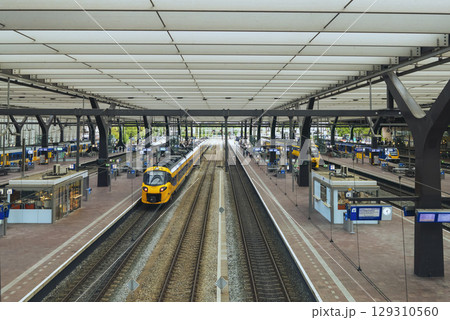 ROTTERDAM, NETHERLANDS, August 1, 2025. Yellow and blue NS train on the platform of Rotterdam Central Station with passengers 129310560