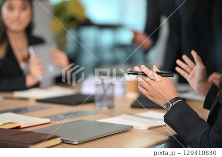 Close up of a businesswoman hands holding a pen while discussing ideas in a modern office Close up of a businesswoman hands holding a pen while discussing ideas in a modern office 129310830
