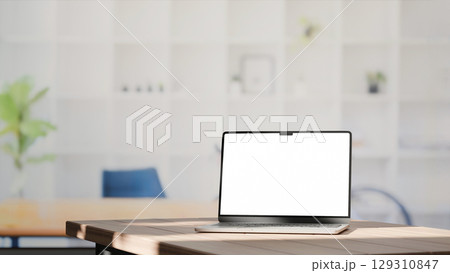 Blank screen laptop on a wooden desk in modern minimalist office with bright natural lighting 129310847