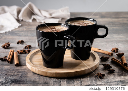 Chai Latte in Black Mug with Spices( star anise and cinnamon) on wooden table. Copy space Chai Latte in Black Mug with Spices( star anise and cinnamon) on wooden table. Copy space 129310876