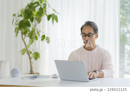 ノートパソコンで作業をする60代前半の男性 129311125