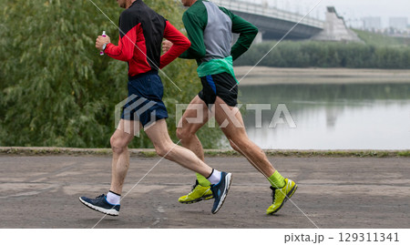 two older runners running in river embankment marathon race 129311341