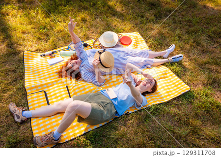 Caucasian mother and daughter spending summer day together in the park on a blanket. Concept of female connection, therapy, and family support. Top view 129311708
