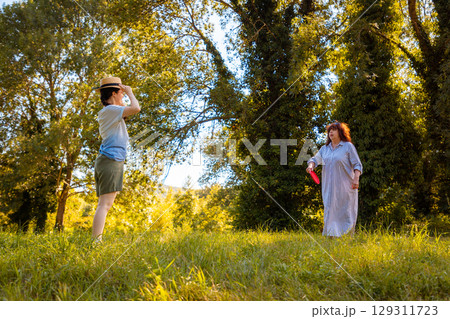 Middle aged mother and her teenage Caucasian daughter play frisbee and laugh together in a sunny green park. Concept of active family weekend, summer vacation and outdoor fun. Middle aged mother and her teenage Caucasian daughter play frisbee and laugh together in a sunny green park. Concept of active family weekend, summer vacation and outdoor fun. 129311723