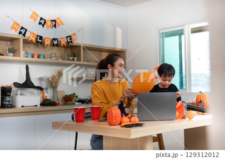 Halloween Activities. Mother and child engaging in festive preparations with joy. Halloween Activities. Mother and child engaging in festive preparations with joy. 129312012