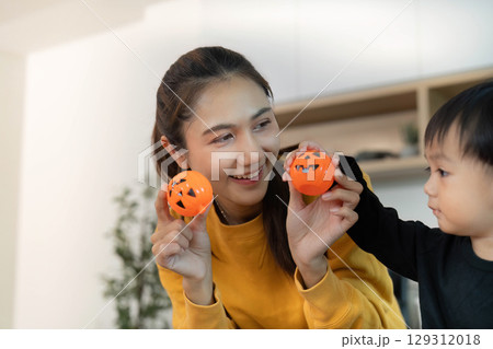 Halloween Celebration. Mother and child enjoying festive activities with pumpkin decorations. 129312018