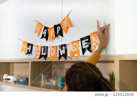 Halloween Celebration. Decorated home with festive banners and a child preparing for trick-or-treating. Halloween Celebration. Decorated home with festive banners and a child preparing for trick-or-treating. 129312020