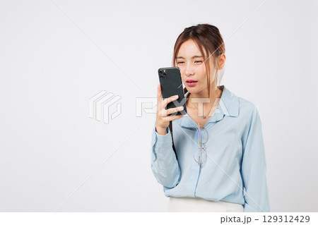 Myopia vision problem. Myopia affects Young Asian woman looking at phone screen closely, eye strain and eyesight loss due to mobile use. isolated studio white background, Poor Eyesight Concept 129312429