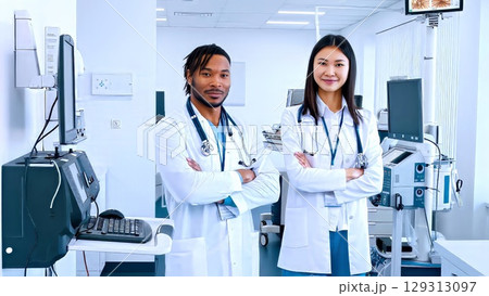 Professional medical team standing side by side, arms crossed, in sleek healthcare setting, highlighting collaboration and expertise 129313097