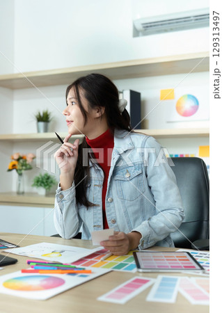 Young Female Designer Pondering Color Choices in Bright Office 129313497
