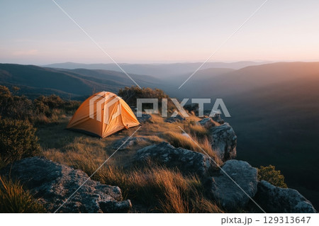 Golden Camping Tent at Sunrise Overlooking Serene Mountain Valley Golden Camping Tent at Sunrise Overlooking Serene Mountain Valley 129313647