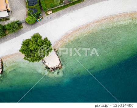 Aerial drone view of Lago di Garda (lake Garda) coastline, Italy. The beach and fresh blue water. Aerial drone view of Lago di Garda (lake Garda) coastline, Italy. The beach and fresh blue water. 129314400