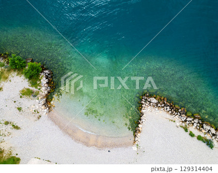 Aerial drone view of Lago di Garda (lake Garda) coastline, Italy. The beach and fresh blue water. Aerial drone view of Lago di Garda (lake Garda) coastline, Italy. The beach and fresh blue water. 129314404
