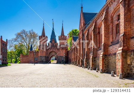 Entrance gate and stone walls of Hradec nad Moravici Castle in the Czech Republic, showcasing Gothic revival architecture surrounded by greenery in a peaceful historic setting. 129314431