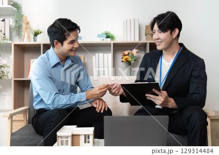 Real Estate Meeting. Professionals exchanging ideas over property plans with a model house. 129314484