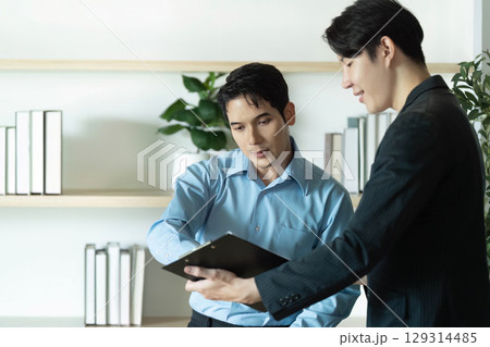 Business Consultation. Professional men reviewing project details in modern office setting. 129314485