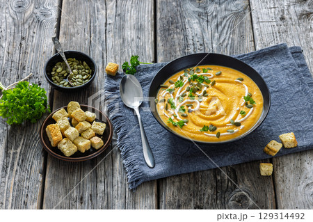 roasted pumpkin puree soup in a black bowl roasted pumpkin puree soup in a black bowl 129314492