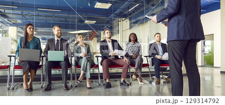 Man speaking on a business meeting in modern office in front of a group of company employees. Man speaking on a business meeting in modern office in front of a group of company employees. 129314792